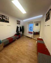 TA WingTsun Linden-Limmer - Umkleide- oder Aufenthaltsraum mit Sitzbänken, Spiegel, Garderobe und funktionaler Ausstattung für Vorbereitung und Nachbereitung vor dem Training.