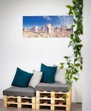 Sitzgelegenheit aus Europaletten mit Kissen. An der Wand hängt ein Bild von Strandkörben. Im Vordergrund hängt Efeu.