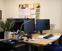Büro mit 2 Arbeitsplätzen und einer vollen Pinnwand.