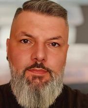 Mann mit Bart schaut freundlich in die Kamera.