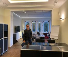A. Hampel in den Büroräumen der PAKT Gruppe mit Blick auf den offenen Arbeits- und Besprechungsbereich.