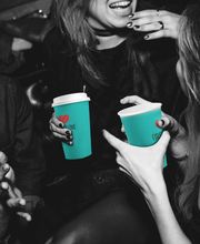 FirstLoveCoffee GmbH - Kaffee Catering Berlin - Gäste mit gebrandeten Kaffeebechern auf Event, ideal für Markenauftritt, Kaffee Catering, Business-Veranstaltung und mobile Barista-Bar.