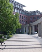 Ein Bild vom Innenhof mit Bäumen und Bänken und einem abgestellten Fahrrad.