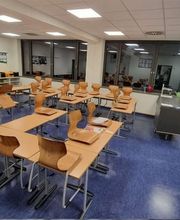 E&E Gebäudereinigung Gründlich gereinigter Klassenraum mit glänzendem blauem Bodenbelag, ordentlich aufgestellten Stühlen und einem gepflegten, hygienischen Gesamteindruck für ein angenehmes Lernumfeld.