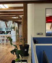 Blick auf die Küche mit Stehtisch und Stühlen und auf zwei Arbeitsplätze mit Bildschirmen. 