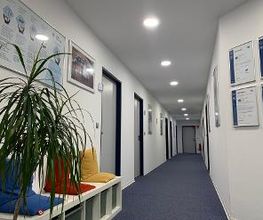 Flur mit kleiner Sitzbank und bunten Kissen. An der Wand hängen verschiedene Bilder im Rahmen.