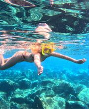 mujer blanca en agua cristalina del mar haciendo snorkel