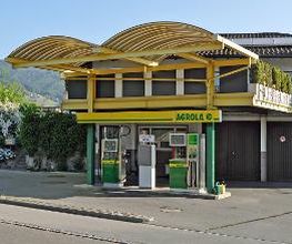 AGROLA Tankstelle in Altstätten, St. Gallen, Überdachung, gelbes Gerüst. Zwei Tanksäulen mit einem Zahlterminal. Im Hintergrund Wohnhaus.