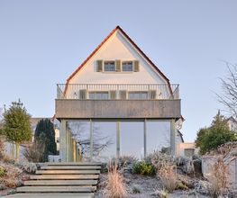 Die Gartenansicht der modernisierten Stadtvilla verbindet historische Substanz mit zeitgemäßer Leichtigkeit. Große Glasflächen, ein filigraner Balkon und fein abgestimmte Grüntöne schaffen eine harmonische Verbindung zwischen Alt und Neu.