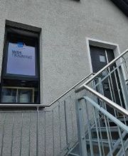 Gebäudeansicht von außen mit Treppe zum Haupteingang. Fenster mit WBS TRAINING Aufschrift und Logo.