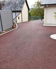 Cours réalisée en enrobé rouge Stardraine avec un pavage la Couture pour y poser un arbuste. Chantier au Trait 76580