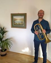 Ein Bass-Flügelhorn wird in Position in einem hellen Innenraum gehalten.