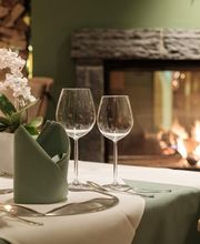 In alpinen Farben eingedeckter Tisch neben dem gemütlichen Kaminfeuer.