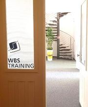 Eingang der an einer Glastür vorbei zu einer Wendeltreppe führt.