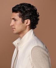 Off-white light padded zip vest designed for a streamlined, hip-length fit. High collar, double-ended zip closure, welted side pockets, and elastic hem. Fully lined and water-repellent for added utility.