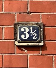 Hauswand mit dem Schild der Hausnummer dreieinhalb.