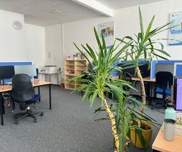 Großer Schulungsraum mit 12 Plätzen zu sehen sind vereinzelnd PC Arbeitsplätze mit großer Bodenpflanze