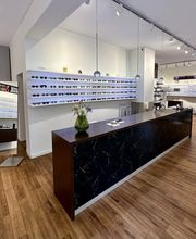 Empfangsbereich von Newels Eyewear in Münster mit modern gestalteter Brillenpräsentation. Zahlreiche Korrektionsbrillen und Sonnenbrillen verschiedener Designs stehen für die persönliche Auswahl und Beratung bereit.