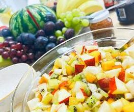 Bild von einem gedeckten Tisch mit Obststalat, einem Obstkorb sowie verschiedenen Aufstrichen und Baguette.