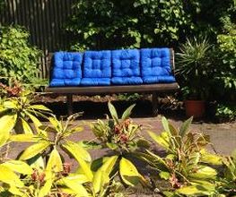 Eine Bank mit blauen Kissen in einem Garten.