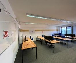 Ein Arbeitsbereich mit mehreren Tischen, auf denen sich Monitore und Computer befinden.