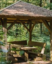 Eine überdachte Sitzgruppe im FriedWald Bremervörde bietet Besuchern Schutz bei unbeständigem Wetter.