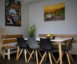 Ein Tisch mit 2 Bänken und Stühlen im Aufenthaltsbereich. An der Wand hängen bunte, fröhliche Bilder.