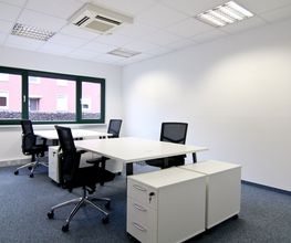 Büroraum mit 4 Arbeitsplätzen. 2 weiße Tische, 4 schwarze Bürostühle, 4 weiße Rollcontainer, Fenster.