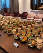 dean&david Catering | Stuttgart - Reihenweise frische Salate im Glas mit separatem Dressing, Wraps und Bowls auf einem langen Buffet für eine professionelle Veranstaltung.