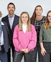 Ein Mann und fünf Frauen posieren für ein Gruppenfoto.