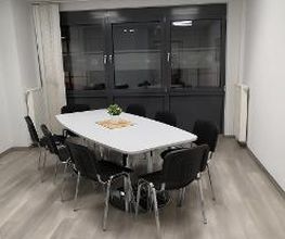 Ein Aufenthaltsraum mit weißem Tisch und mehreren schwarzen Stühlen.