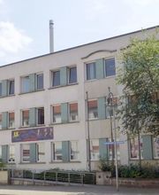 Bild vom Gebäude der Einrichtung. Helle Fassade mit hell-grünen Platten neben den Festern.