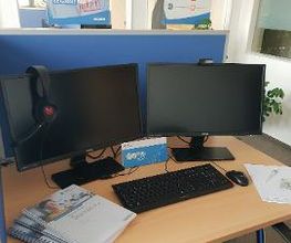Arbeitsplatz für Teilnehmer mit zwei Bildschirmen Tastatur und Maus, dazu noch ein paar Unterlagen zum lernen
