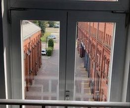 Fenster mit Aussicht aus der zweiten Etage auf Backsteingebäude.