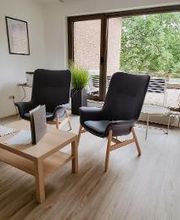 Zwei gemütliche Sessel mit Tisch im Pausenraum mit Blick auf die Terrasse mit Gartenmöbeln.