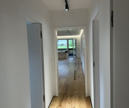 Moderner Flurbereich mit wandbündigen Filomuro-Türen, Q4-Oberflächen, hochwertigem Parkettboden und integrierter 48-V-Magnetschienenbeleuchtung.