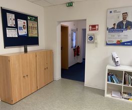 Ein Flur mit 2 Schränken links und einem Bücherregal rechts. An der Wand ein WBS TRAINING Plakat, daneben eine Tür zum Flur.