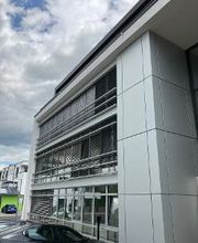 Außenansicht des Gebäudes. Graue Fassade und Fensterfront.