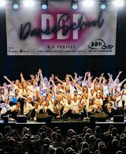 D.D.Project - Hip-Hop Tanzschule Dresden Gruppenfoto einer Tanzformation auf einer Wettbewerbsbühne mit starker Bühnenbeleuchtung und begeistertem Publikum.