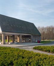 Auch in den Außenanlagen begegnet die Kapelle dem Verkehr der Autobahn mit Ruhe. Die Skulptur, ein Wassersprudelbecken und verschiedene Sitzgelegenheiten lassen den Aufenthalt zur Entspannung werden.

Westlich der Kirche steht eine Stahlskulptur von dem Soester Künstler Michael Düchting. Sie trägt den Titel "Das Tor". Es handelt sich um eine sechs Meter hohe und rund 7,5 Tonnen schwere Plastik aus Stahlplatten mit einem schmalen Durchgang in der Mitte. Der Bildhauer beschreibt sein Kunstwerk als Metapher für die aktuelle Reise wie auch für das unterwegs Sein im Leben.