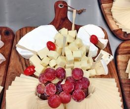 Liebevoll angerichtete Käseplatte auf Holzbrett mit Weintrauben und Weichkäse. Hochwertiges Fingerfood & Kaltspeisen-Catering von Christians Catering in Bernburg & Region.