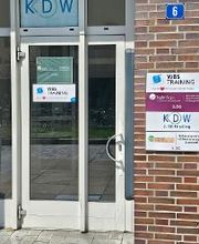 Eingangsbereich mit Beschilderung. Eine Glastüre mit weißen Rahmen und einem WBS TRAINING Türschild auf dem steht „Unser Herz schlägt für Bildung“.