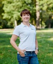 Eine Frau mit kurzen, dunklen Haaren in Jeans und weißem Poloshirt.