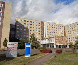 Bürogebäude mit Straße davor. Auf dem Rasen sind zwei Firmenschilder zu sehen.