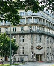 Das Außengebäude der WBS TRAINING (und anderen Unternehmen) als Eckansicht vom Willy Brandt Platz her fotografiert. Schönes, altes Gebäude, grauer Stein, große Fenster, Balkone in den oberen Etagen.