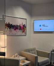 Gemütliche Sitzecke bestehend aus 2 hellen Sesseln. An der Wand hängt ein Bild und ein Fernseher mit der Aufschrift „WBS TRAINING - Unser Herz schlägt für Bildung“.