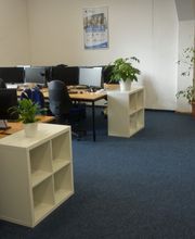 Schulungsraum mit mehreren PC-Arbeitsplätzen und einer orangenen Couch.