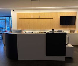 mediaService Bremen | Full-Stack Werbeagentur - Der modern gestaltete Empfangstresen im Eingangsbereich einer Agentur mit einer stilvollen Holzlamellen-Wandverkleidung, Monitor und edler Beleuchtung.