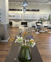 Detailaufnahme des stilvollen Innenraums von Newels Eyewear in Münster. Der Beratungsbereich mit Blumenarrangement und Brillenwänden unterstreicht die persönliche und moderne Atmosphäre des Augenoptikfachgeschäfts.
