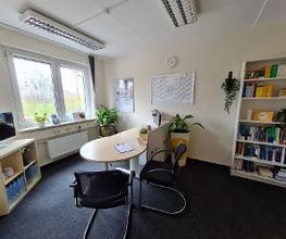 Ein Büro mit Schreibtisch und Regal.